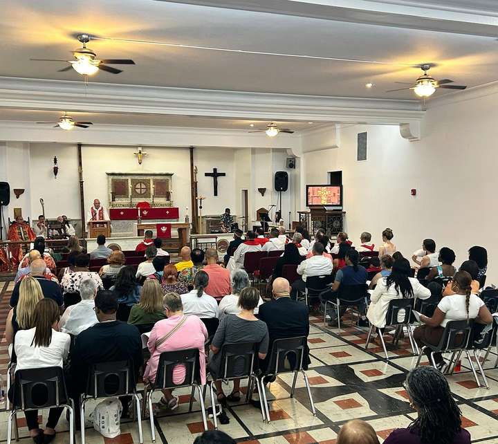 A full service at Our Saviour, seen from the back of the sanctuary, with the congregation seated and clergy in red vestments at the altar